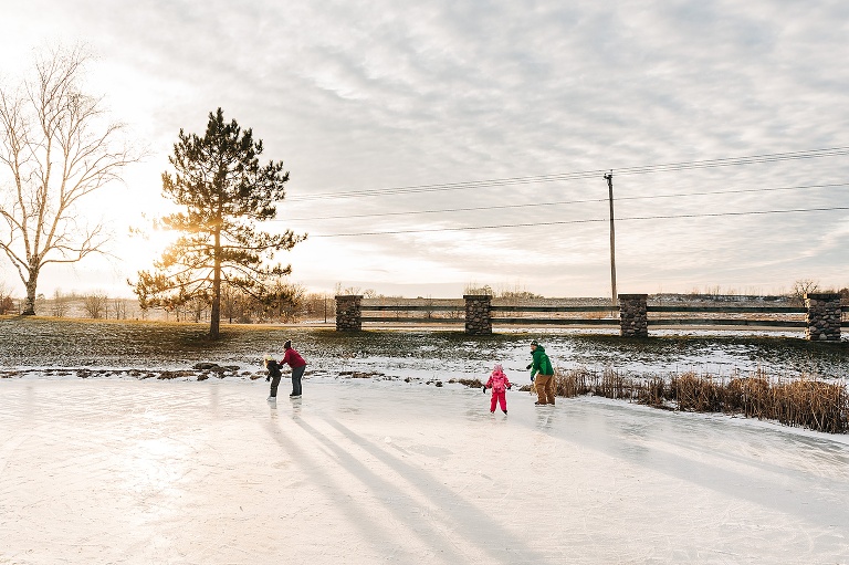 family of four ice skating on a frozen pond at sunset 