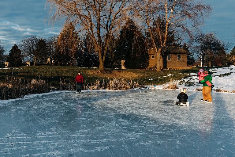 dramatic light of family of four ice skating on a frozen pond 