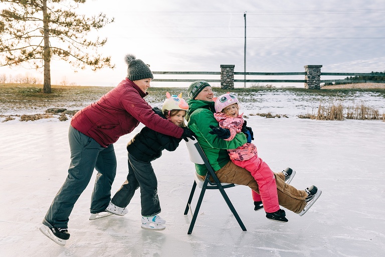 Family of four ice skates on a pond at sunset 