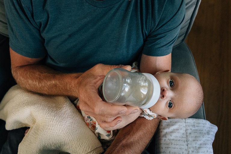Baby gets a bottle while on dad's lap