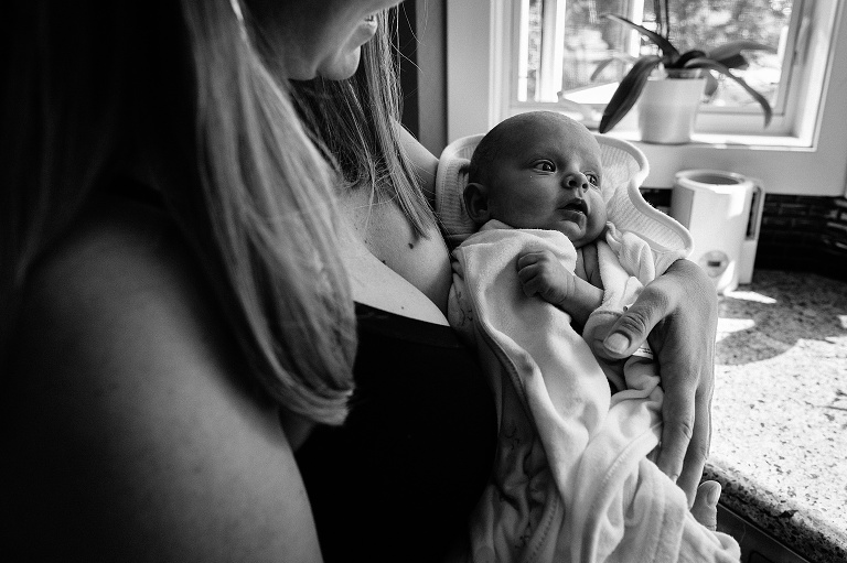 Baby held by mother in window light and wrapped in a towel