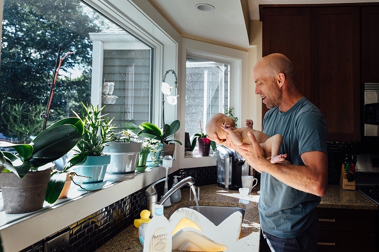 dad holds baby getting ready for a sink bath