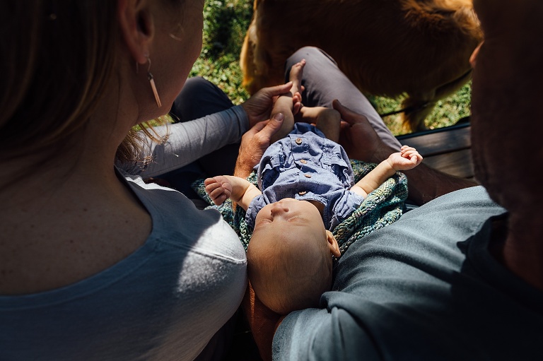 top down view of parents holding baby on a park bench
