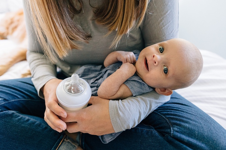 baby smiles and makes eye contact with camera in mother's arms