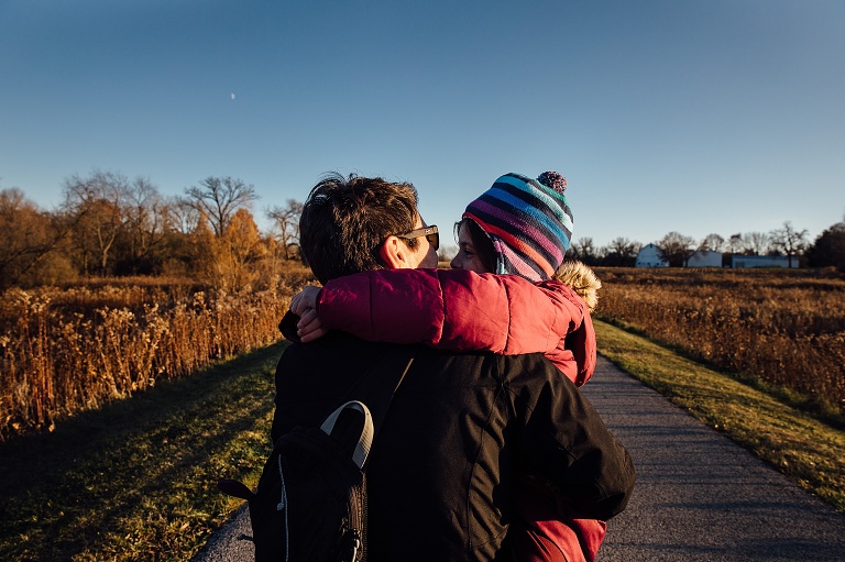 mom and girl look at each other on a cold autumn day. Partial moon in a deep blue sky
