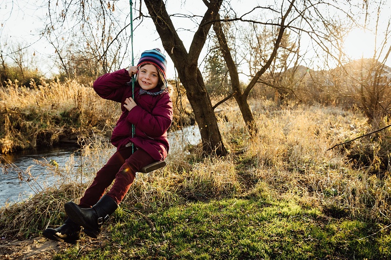 girl swings on a rope and wood bench swing on an autumn day