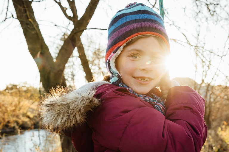 girl holds a rope with sunflare near her eye 