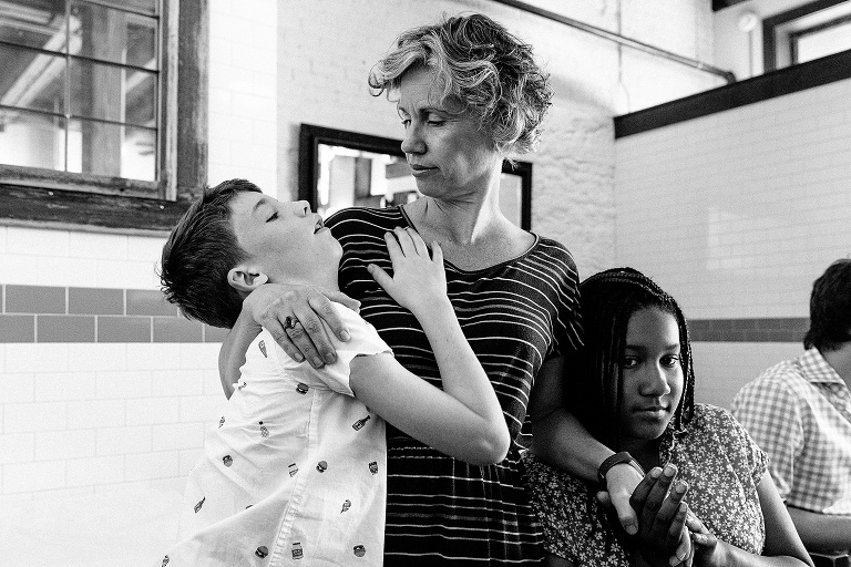 young and preteen girl hang on mother with bored expressions