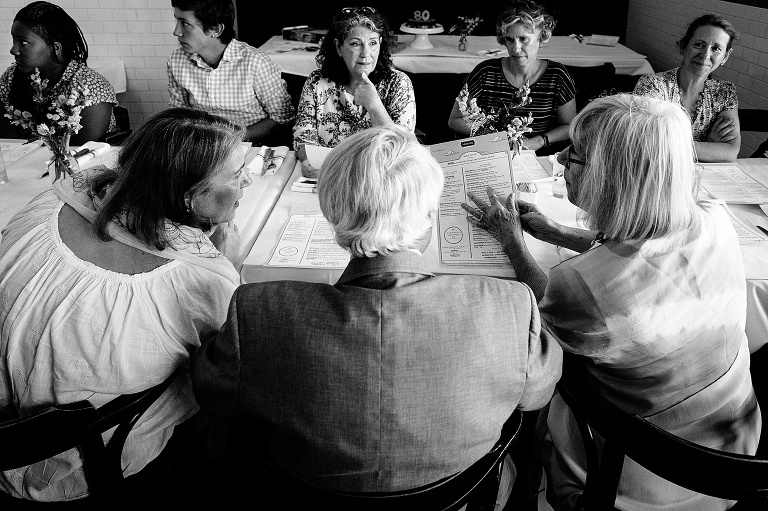 black and white; people at a long restaurant table examining the menu