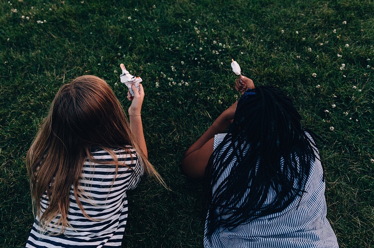 top view of two girls enjoying a Dilly Bar in the grass at an event photography session
