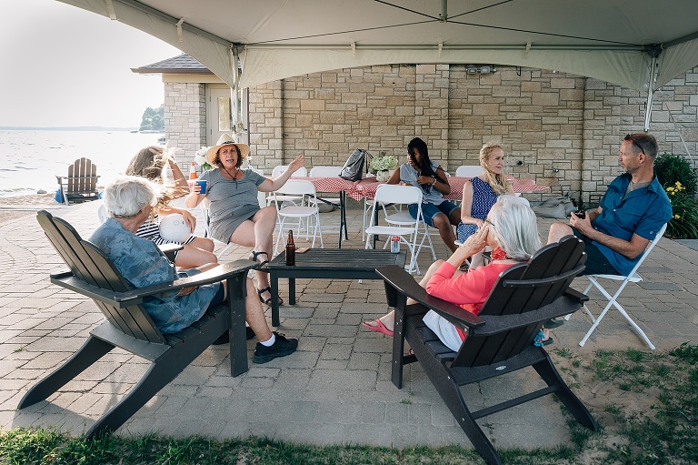 seven people talk in a circle on a windy day at the lake for an event photography session