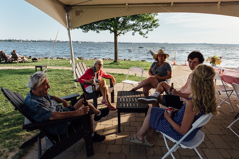five people gather under a tent at the beach, talking, for an event photography session