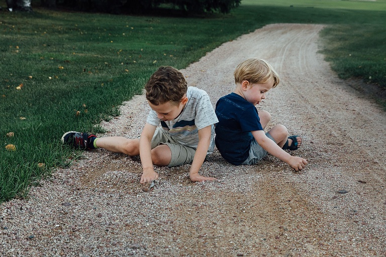 two young boys play in the gravel of a road at the end of a summer night Backyard Summer Nights