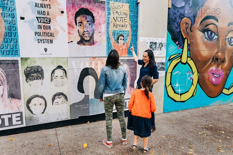 Mother points to vibrant anti-racist murals in downtown Madison while her children follow her point