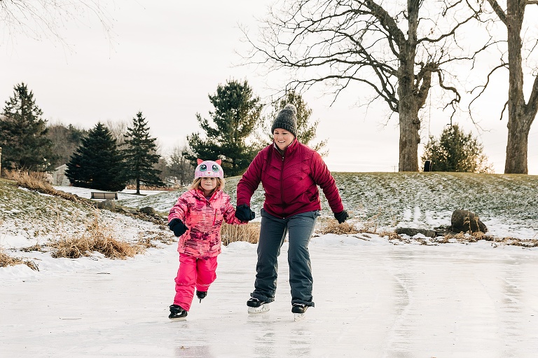 mom ice skates on a pond with young daughter 