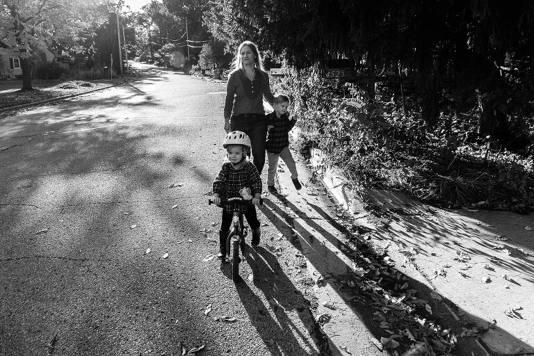 Mother walks next to children in beautiful sunlight on a road