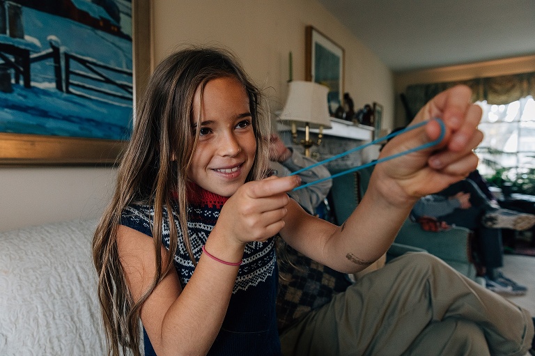Girl stretches out a rubber band in the ready-to-shoot gesture and smiles