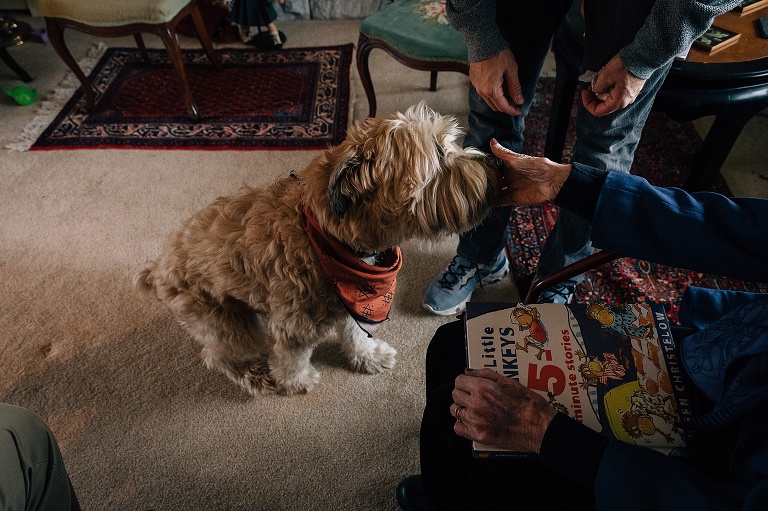 Great-grandmother pets dog in the living room.