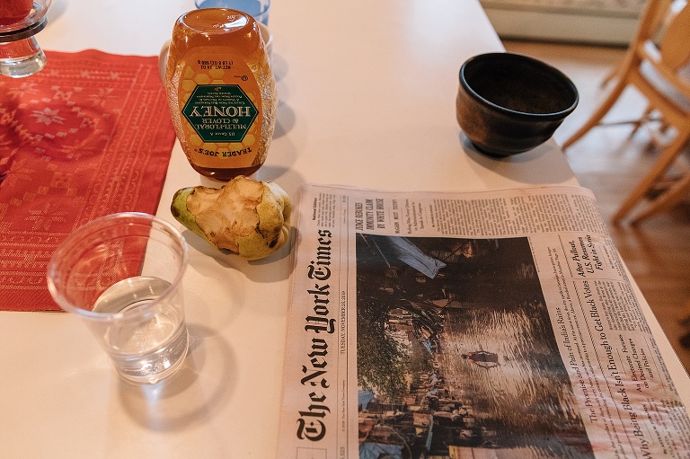 Half eaten pear, upside down honey jar, and a copy of the New York Times sits on the kitchen counter.