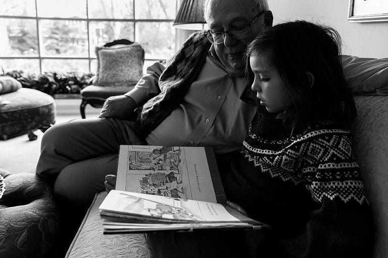 grandpa and grandson read a book together on a couch. Black and white.