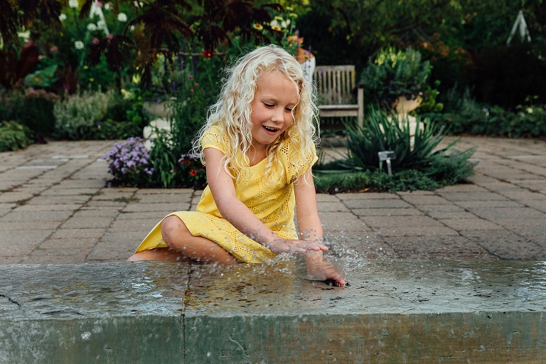 Girl in yellow dress plays in water fountain at Olbrich Gardens