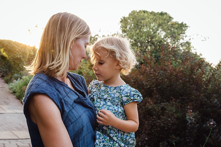 Mom holds young daughter in serene moment as sun sets at Olbrich Gardens