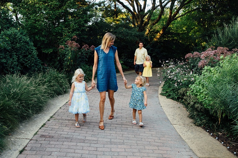 Mom holds two daughter's hands and Dad and third daughter follow on the path