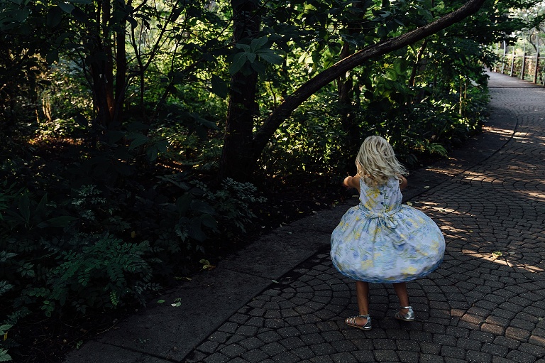 Girls spins her dress in a pouffy circle on top of a circular brick path