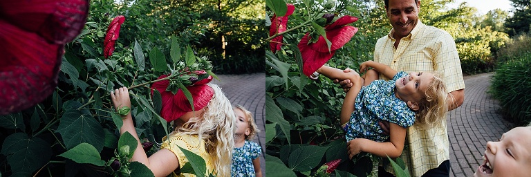 Girl smells huge red hibiscus flower at Olbrich Gardens