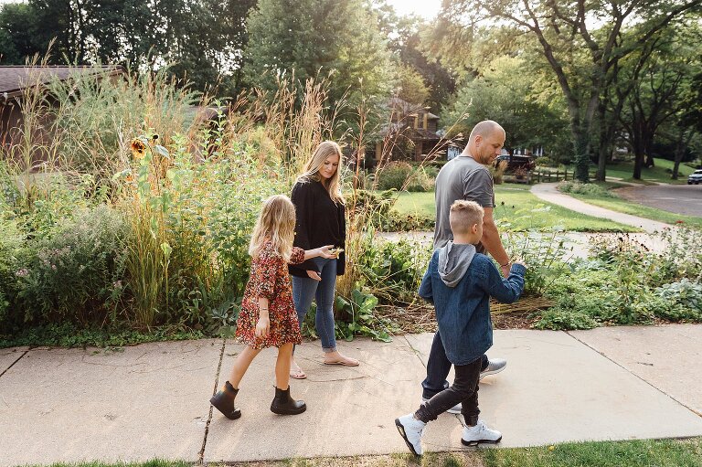 Family of four walk next to tall grasses on fall day
