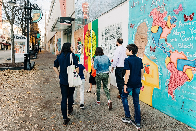 family of six walks in front of colorful murals in downtown Madison. 