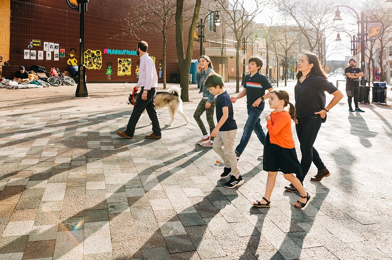 Family of six and a dog walk together in afternoon light in downtown Madison