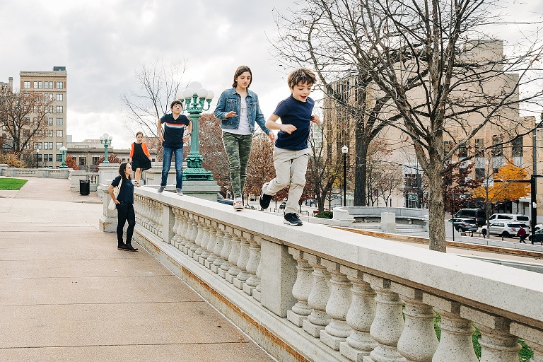 Mom and her four kids walk on the cement railing at the Capitol building in downtown Madison