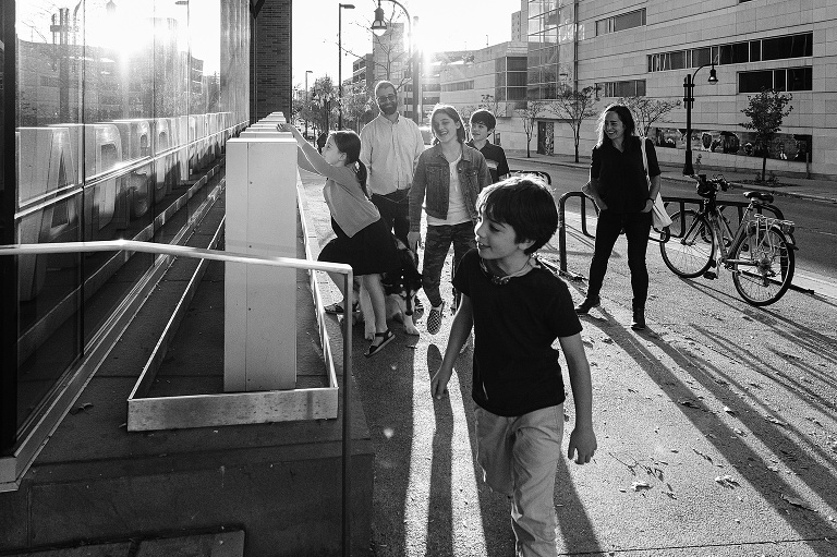 Black and white. Family of 6 climb on letters of Madison library sign.