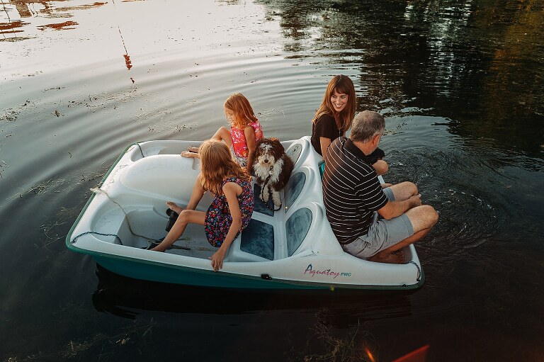 family of four ride on paddle boat with dog. 