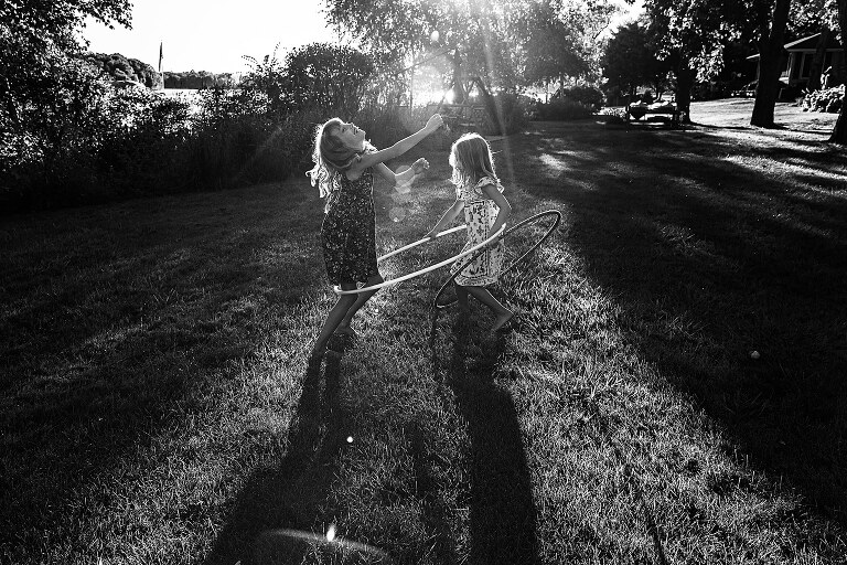 Two girls play with hula hoops in the backyard. 