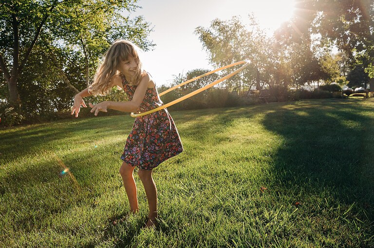 Girl plays with hula hoop in the grass.