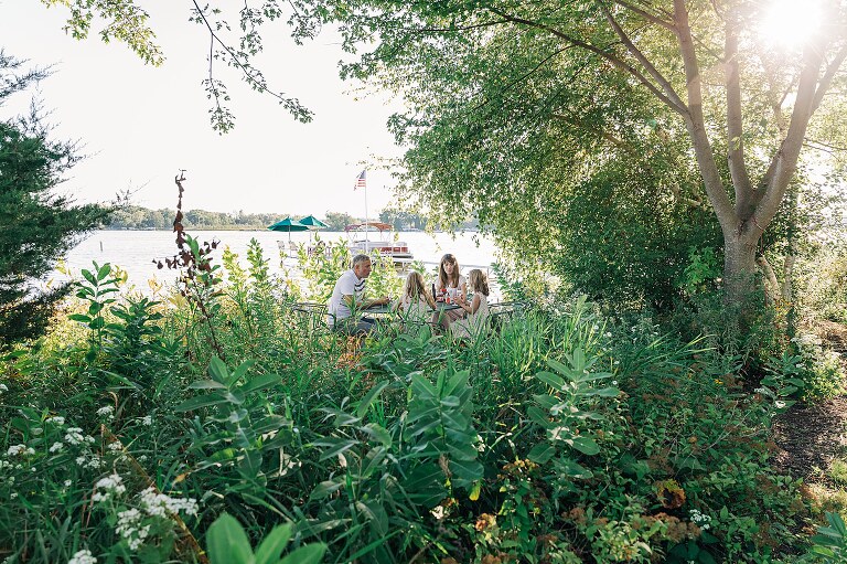 family of four eats ice cream outside near lake. 