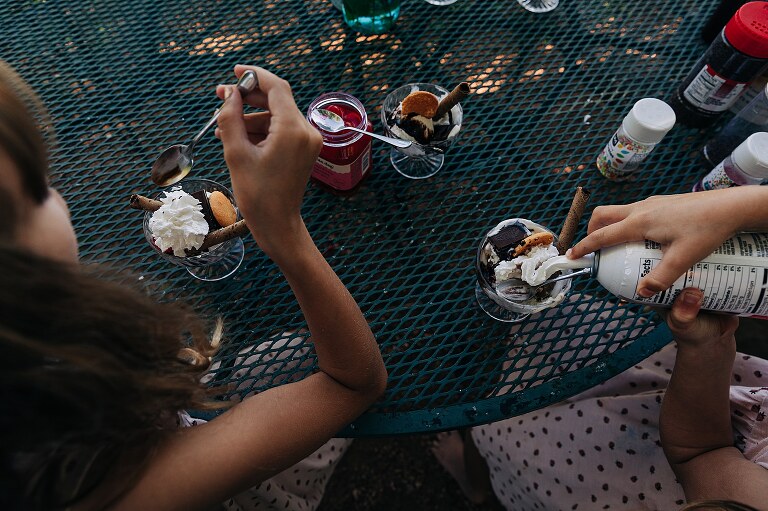 girls eat ice cream sundaes at metal table. 