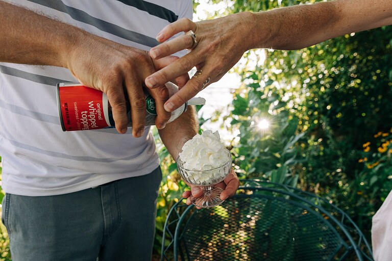 Man pours whipped cream into a small bowl. 