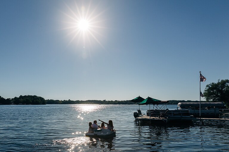 family rides paddle boat on a sunny day. 