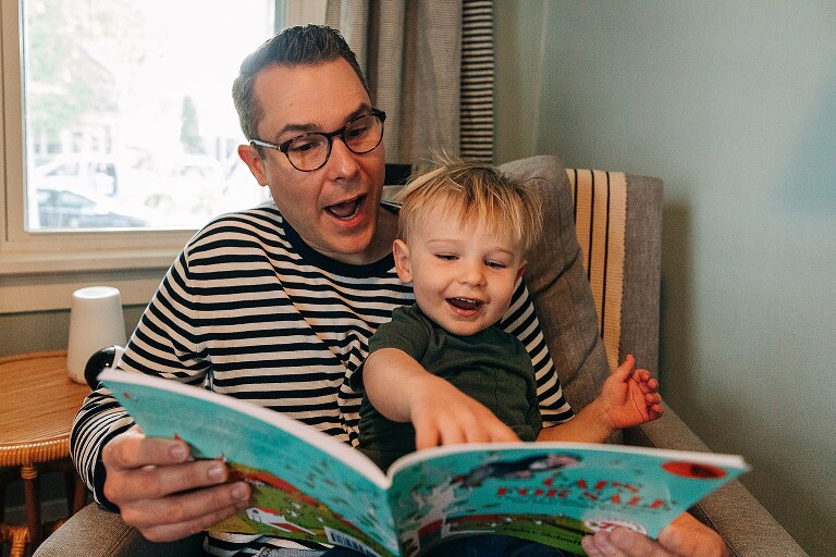 dad and toddler son are very expressive while reading Caps For Sale together