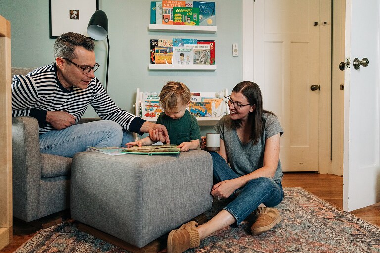 parents and toddler child read books in a bedroom