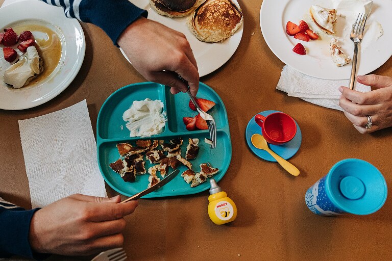 overhead of toddler plate of Saturday pancakes, strawberries and whipped cream