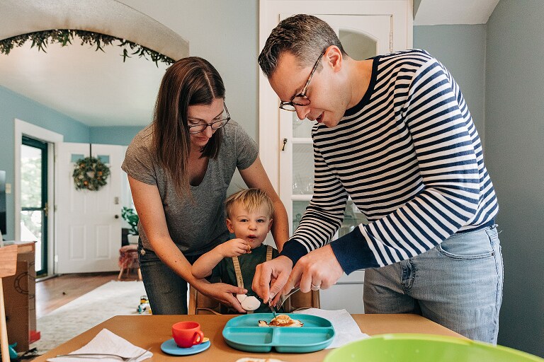 Mom and dad help serve toddler son pancakes 
