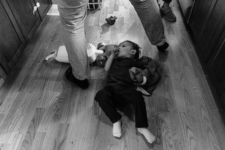 dad steps over son resting on the kitchen floor while making Saturday pancakes 