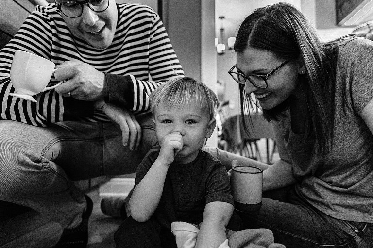 Family three sits on the kitchen floor together on Saturday pancakes day