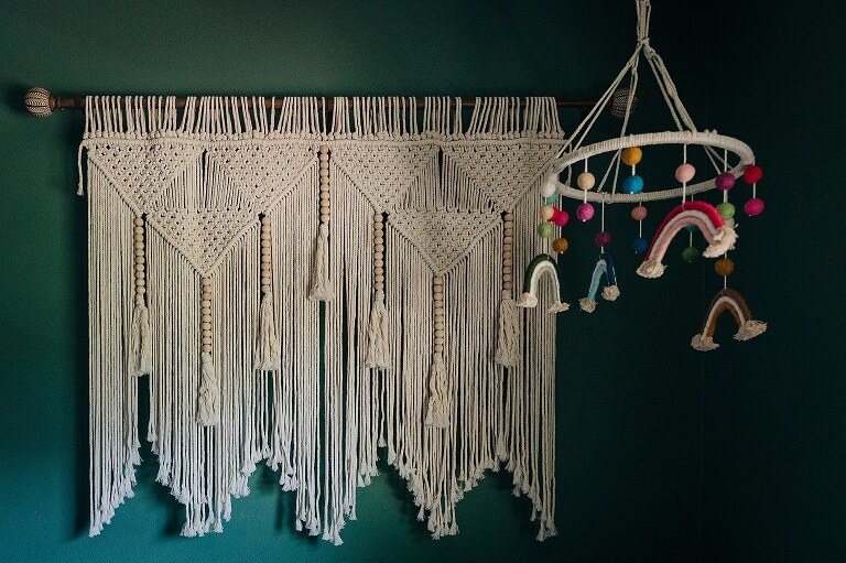 detailed woven wall hanging and rainbow mobile in nursery