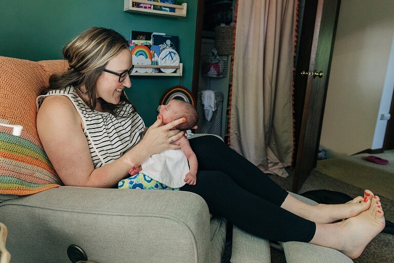 mom smiles at newborn while holding her chin up