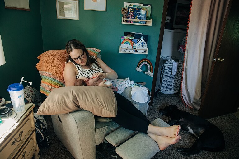 mom nursing newborn in colorful nursery on a quiet summer morning